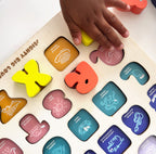 Child's hand interacting with a colorful alphabet puzzle on a white surface
